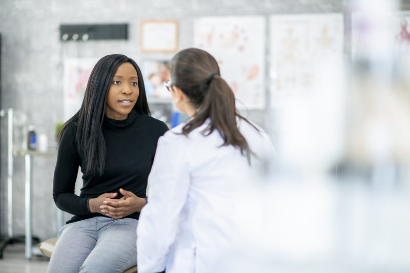 A woman describes her symptoms to her doctor at a medical clinic.